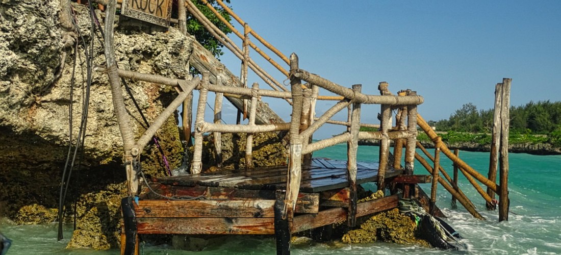 Holzkonstruktion mit Treppe und Schild 'The Rock' führt ins Meer bei Sansibar, Zugang zum berühmten Restaurant The Rock
