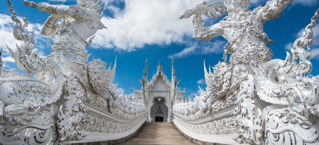 Majestätischer Eingang zum Weißen Tempel in Chiang Rai – Wat Rong Khun Thailand Detailreicher Eingang des Weißen Tempels Wat Rong Khun in Chiang Rai mit imposanten Wächterfiguren