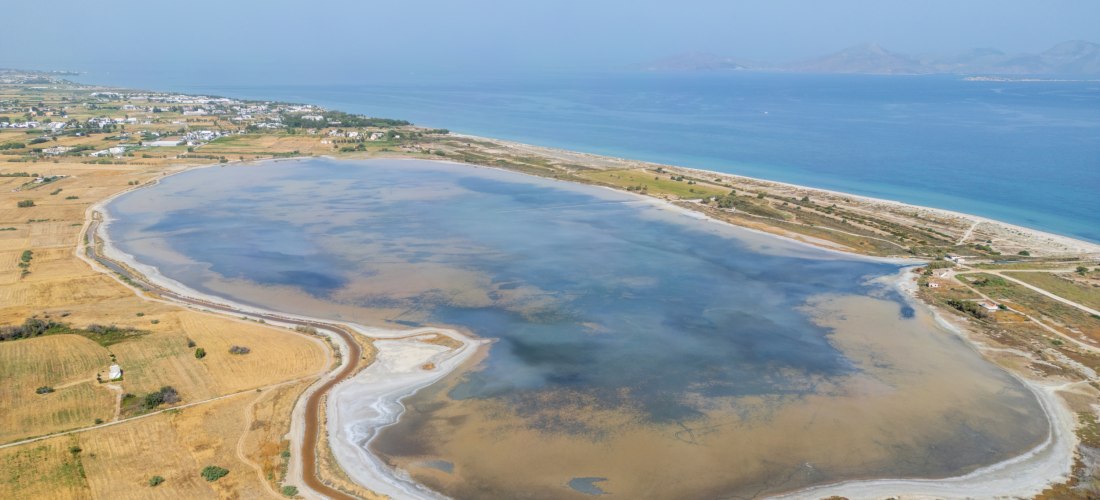 Salzsee Alykes auf Kos aus der Luft, umgeben von Feldern, Strand und der Küste im Hintergrund.