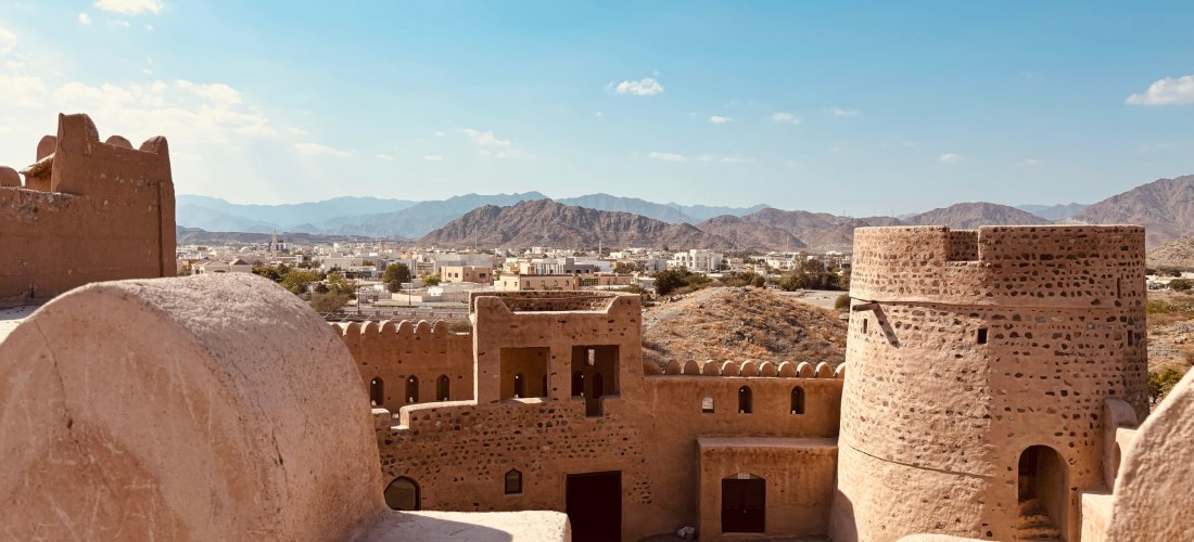 Blick auf die historischen Mauern und Türme des Fujairah Fort mit Panoramablick auf Stadt und Berge. Bedeutendes Wahrzeichen und Highlight in Fujairah.