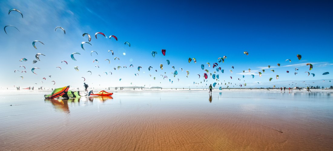 Bunte Kiteschirme am Strand von Essaouira, Marokko – beliebtes Reiseziel für Kitesurfer und Wassersportler an der Atlantikküste.