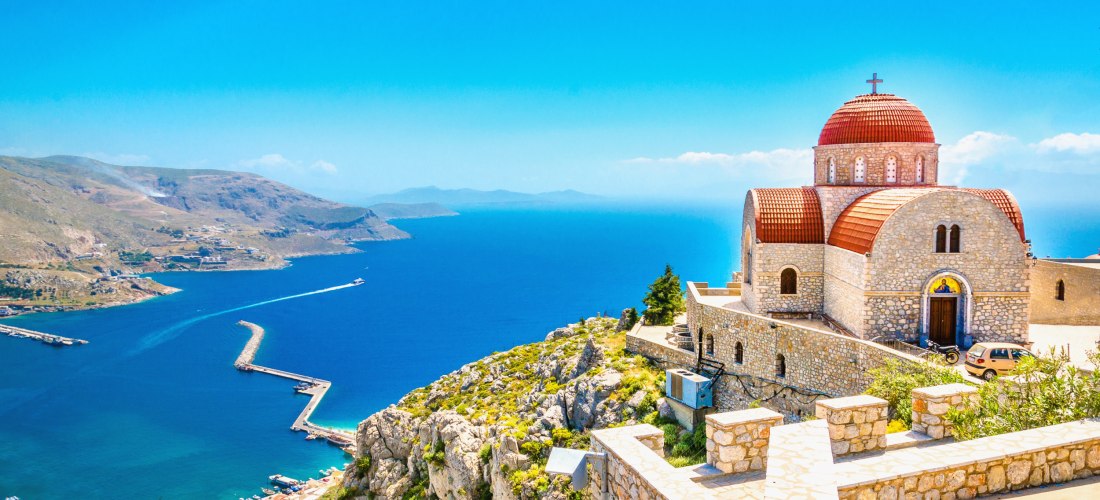 Abgelegene Kirche mit rotem Dach auf einer Klippe, Griechenland