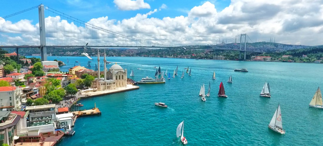 Istanbul am Bosporus: Blick auf die Ortaköy-Moschee mit Regatta-Segelbooten vor der Bosporus-Brücke an einem sonnigen Tag