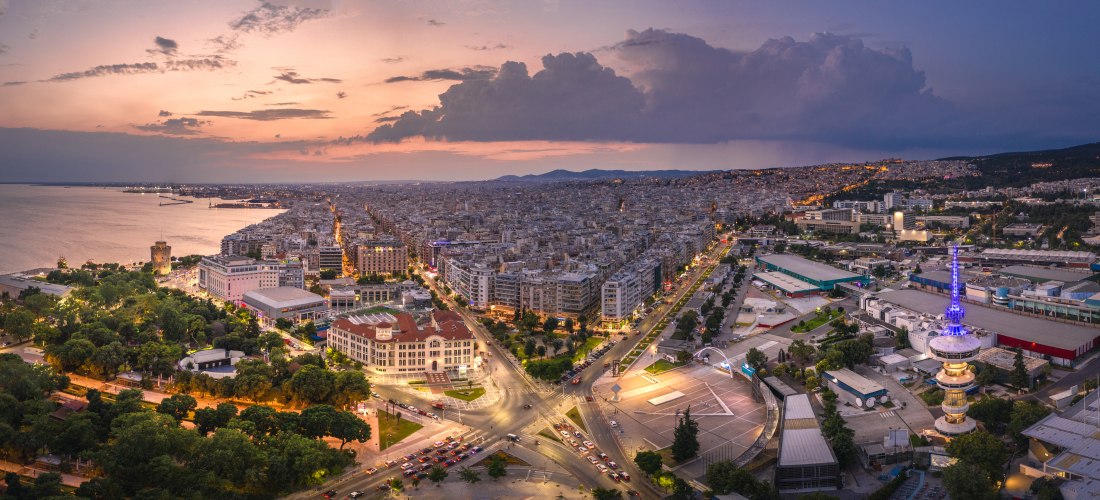 Panoramablick auf Thessaloniki bei Sonnenuntergang mit dem Weißen Turm, Hafen und Stadtlichtern