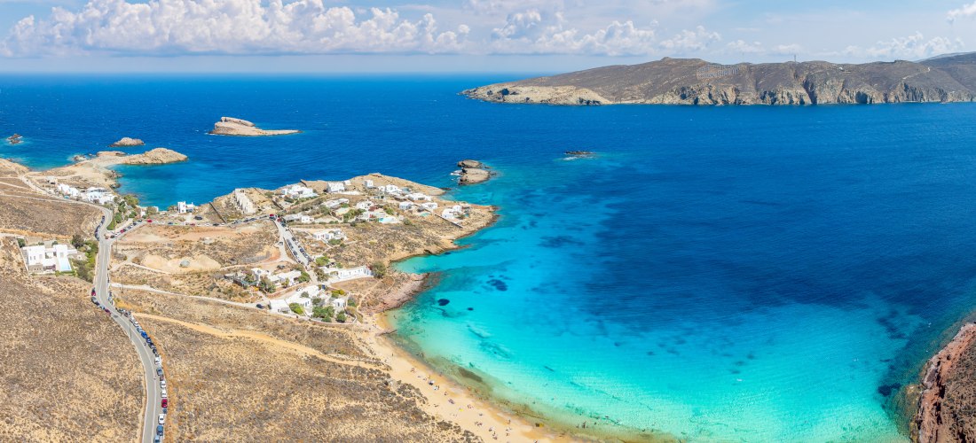 Panoramablick auf den Agios Sostis Beach auf Mykonos mit kristallklarem Wasser, ruhiger Bucht und wenigen Badegästen