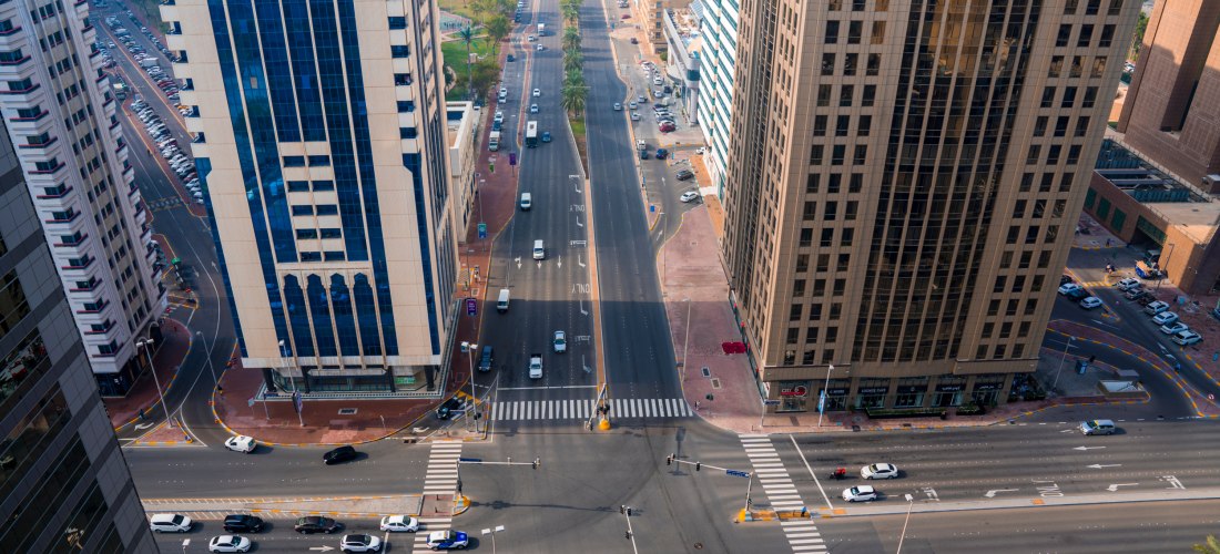 Luftaufnahme einer breiten Straßenkreuzung in Abu Dhabi, umgeben von hohen Wolkenkratzern und Autos auf der Straße