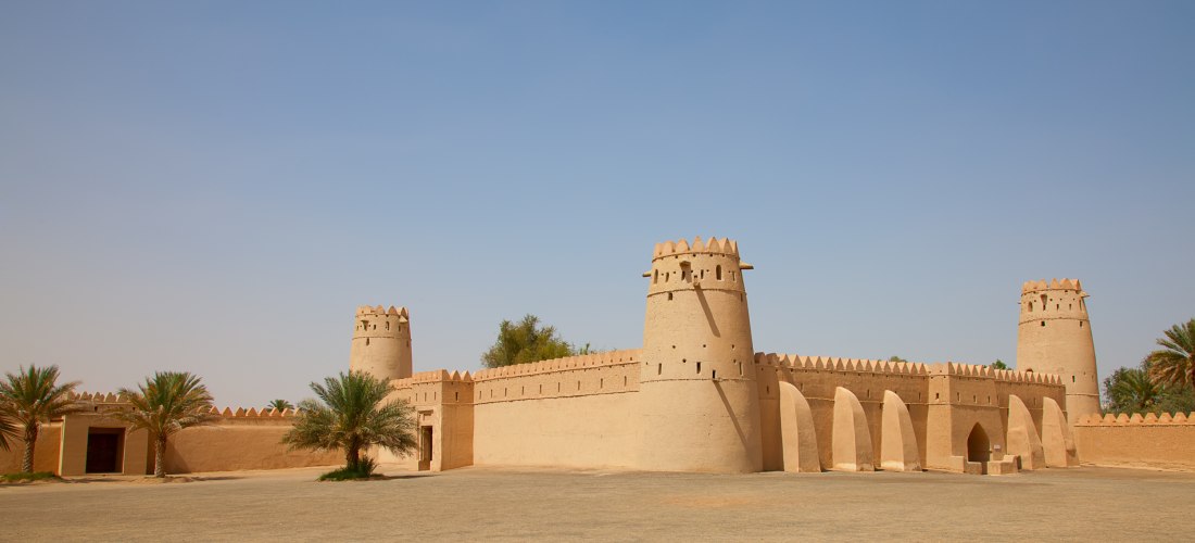 Außenansicht der Al Jahili Festung in Al Ain mit traditionellen Wachtürmen und Torbögen. Historisches Bauwerk und kulturelles Highlight der VAE.