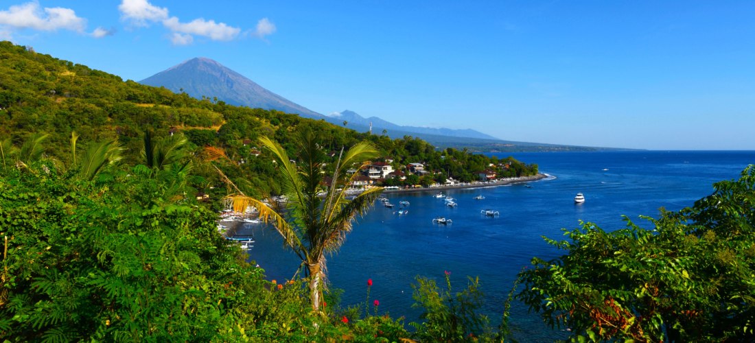 Küstenlandschaft auf Bali mit Blick auf den Vulkan Agung und die Bucht von Amed mit Fischerbooten.