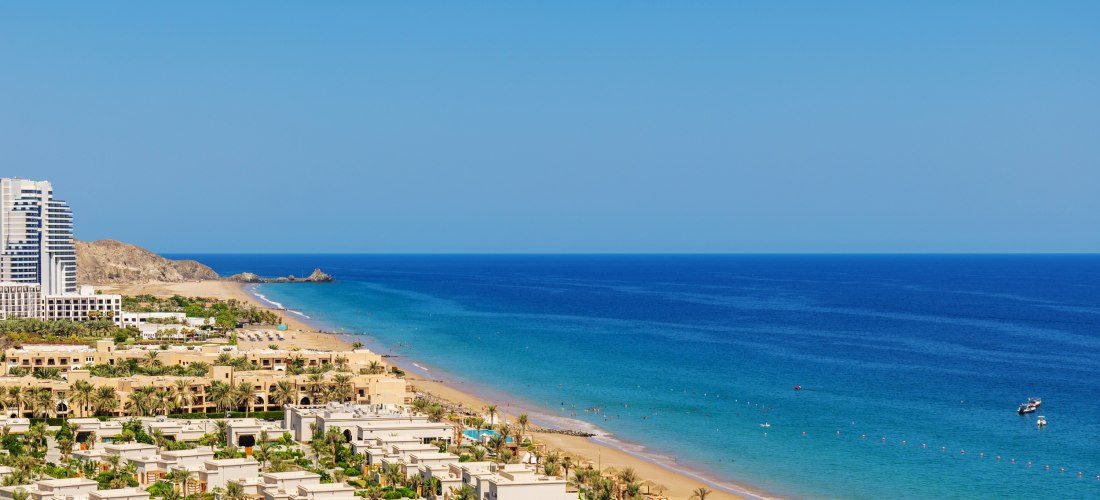 Luftaufnahme vom Strand in Fujairah, Vereinigte Arabische Emirate. Türkisblaues Wasser, feiner Sandstrand, Hotels und Palmen mit Blick auf die Küste des Golfs von Oman.