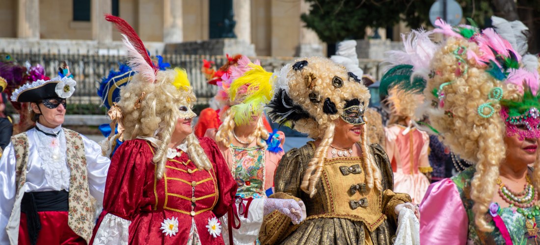 Farbenfroher Festumzug in Korfu-Stadt: Männer und Frauen in reich verzierten barocken Kostümen und kunstvollen Masken feiern den Karneval. Die Atmosphäre ist ausgelassen und erinnert an historische Zeiten – ein kulturelles Highlight im Veranstaltungskalen
