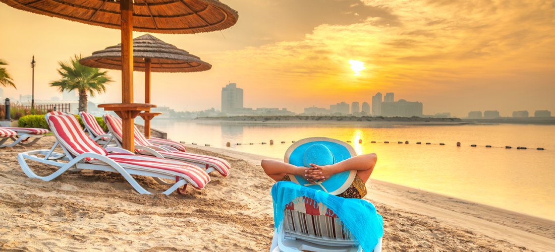 Frau mit Hut auf einer Liege am Strand