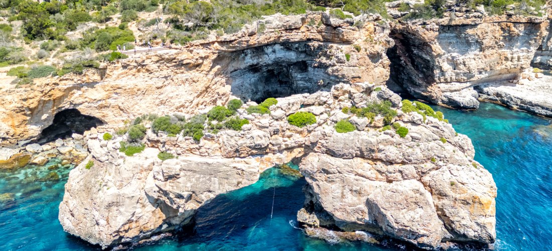 Spektakuläre Felsformation mit natürlichem Felsbogen über türkisblauem Meer an der Küste