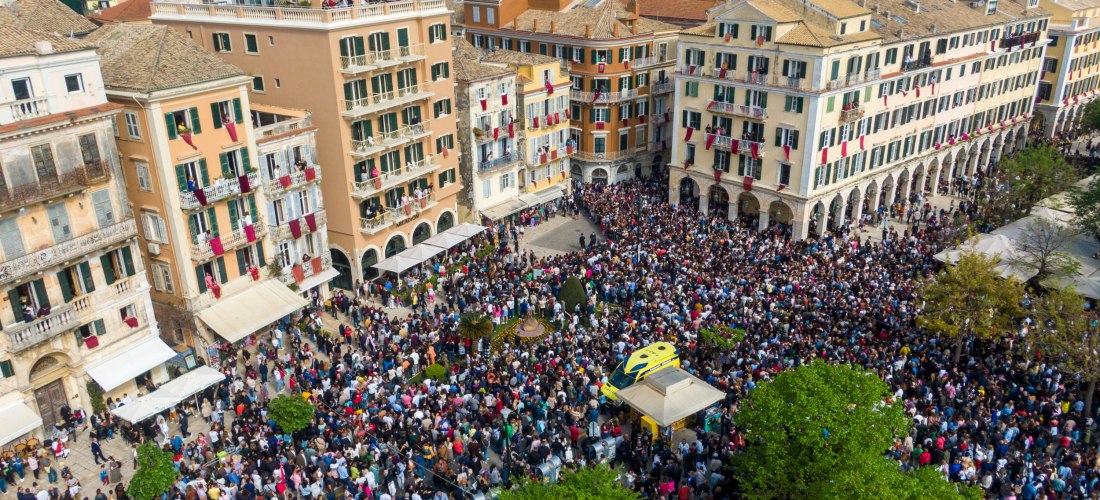 Osterfest in der Altstadt von Korfu: Tausende Menschen versammeln sich rund um das Liston, um das spektakuläre „Töpfewerfen“ live mitzuerleben. Rote Tücher hängen von den Balkonen, während oben die traditionellen Tongefäße zu Boden krachen – ein einmalige