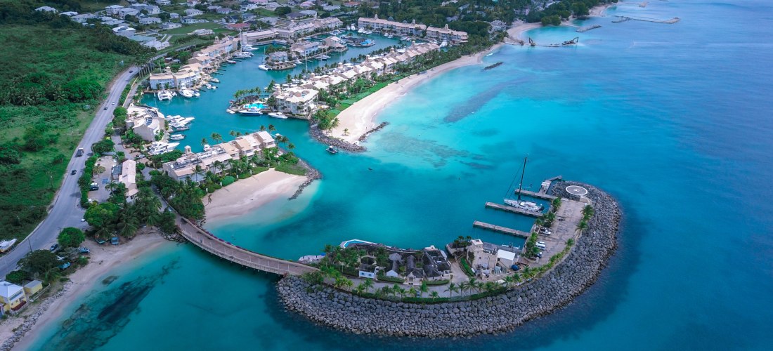 Luftaufnahme eines Yachthafens auf Barbados mit türkisblauem Wasser, Sandstrand und Luxusvillen.