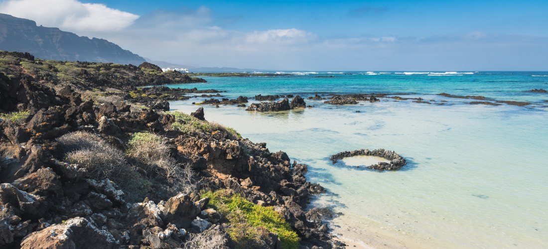 Küste bei Orzola im Norden von Lanzarote mit Lavagestein, türkisfarbenem Wasser und flachen Naturpools.