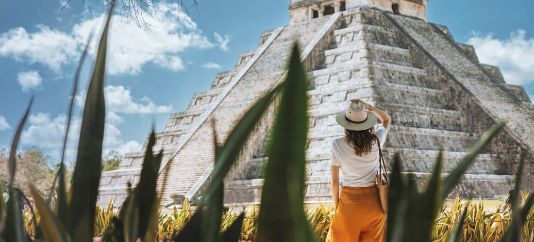 junge Touristin mit Hut steht vor dem Hintergrund der Pyramide des Kukulcan in der alten mexikanischen Stadt Chichen Itza.