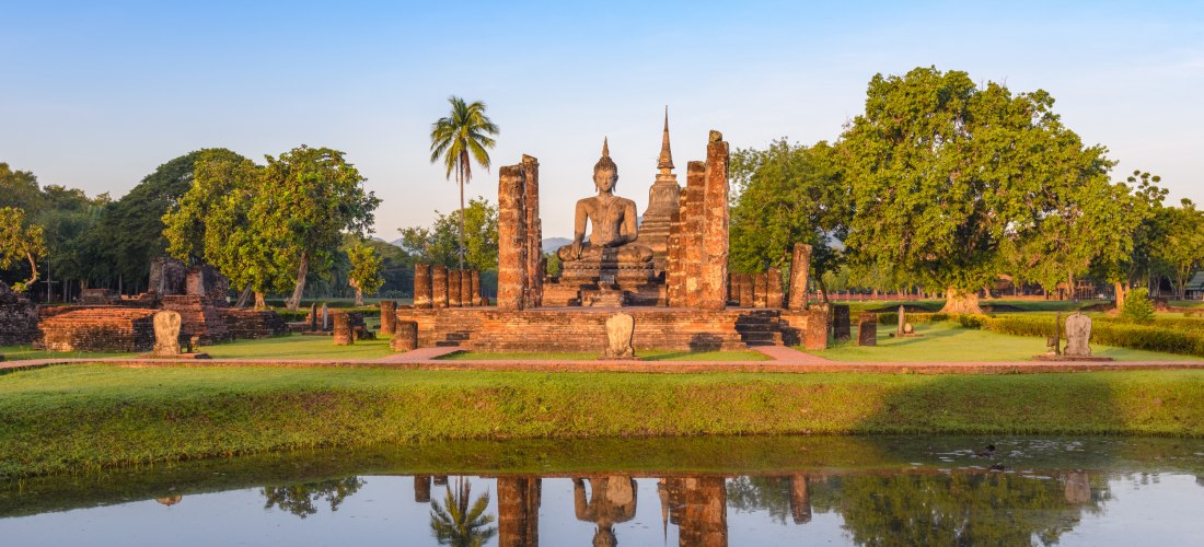 Wat Mahathat in Sukhothai – Historische Buddha-Statue im UNESCO-Weltkulturerbe in Thailand Buddha-Statue und antike Tempelruinen im Wat Mahathat in Sukhothai Historical Park, Thailand
