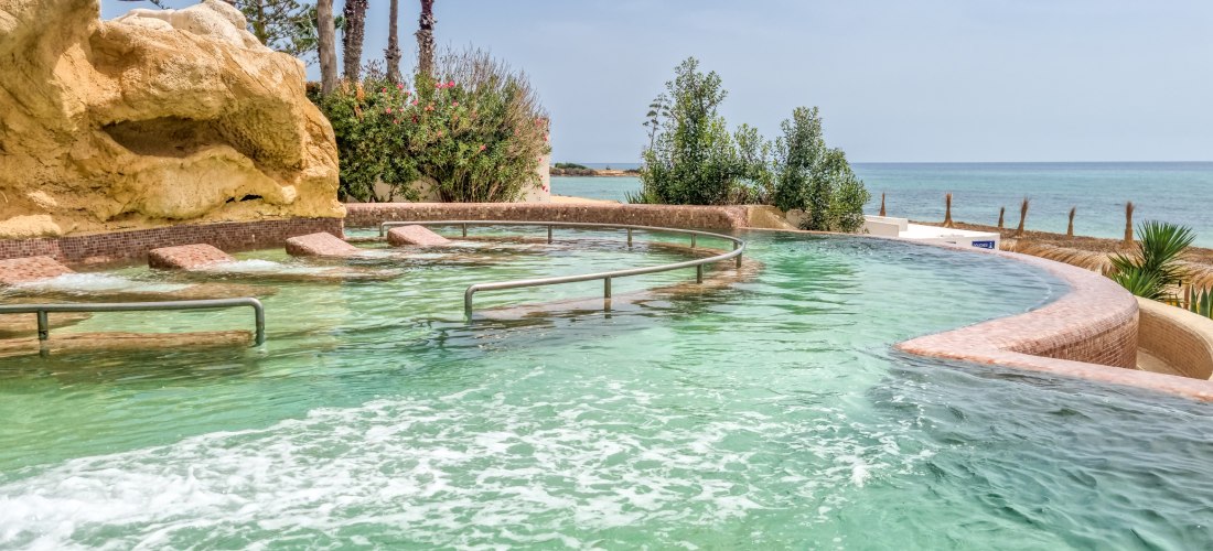 Pool mit Liegen im Wasser, Sonne scheint,Landschaft an einem Strand in Hammamet, Tunesien
