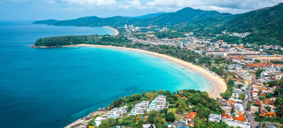 Luftaufnahme vom Kata Beach auf Phuket mit weißem Sandstrand, türkisblauem Meer und grünen Bergen im Hintergrund – einer der schönsten Strände Thailands 2025/2026.