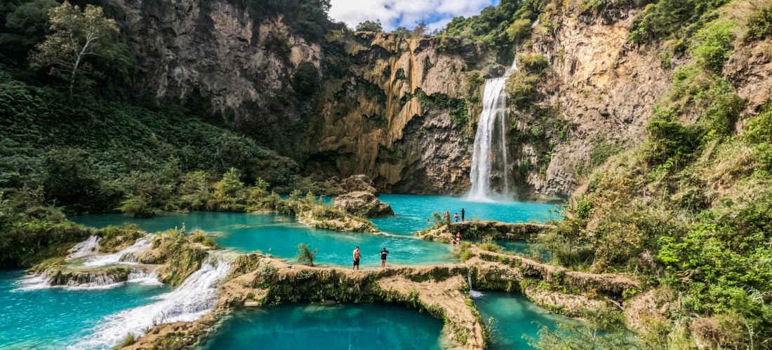 Blick auf den Wasserfall und die natürlichen Pools, umgeben von Felsen und Grün