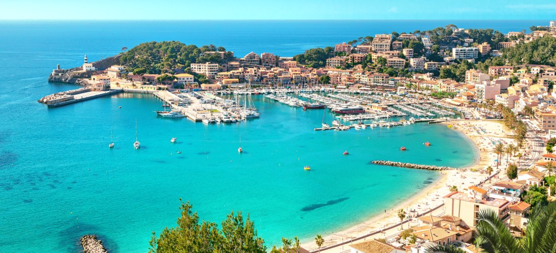 Luftaufnahme von Port de Sóller mit türkisfarbenem Wasser, Sandstrand, Yachthafen und umliegenden Hügeln