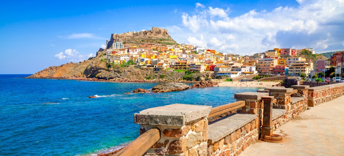 Blick auf Castelsardo an der Nordküste Sardiniens mit bunten Häusern, Burg und tiefblauem Meer – einer der schönsten Orte der Insel