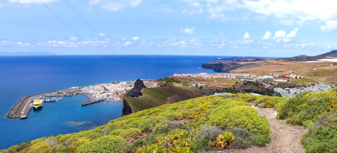 Panoramablick auf den Hafen von Puerto de las Nieves auf Gran Canaria mit Fähre, kleinen weißen Häusern und Küstenlandschaft, die ins blaue Meer übergeht.