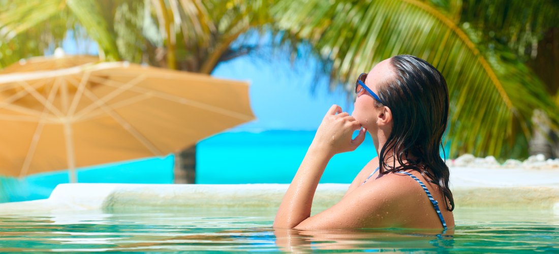Frau mit Sonnenbrille im Pool, Blick auf das wunderschöne Meer