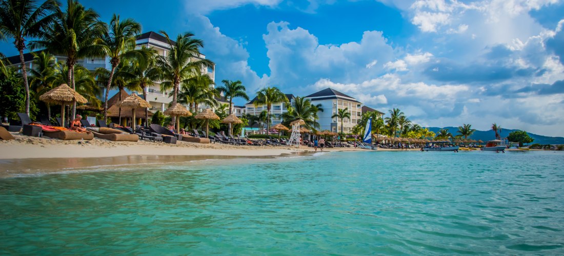Luxuriöses Strandresort in Negril, Jamaika mit Palmen, weißem Sandstrand und türkisblauem Meer.