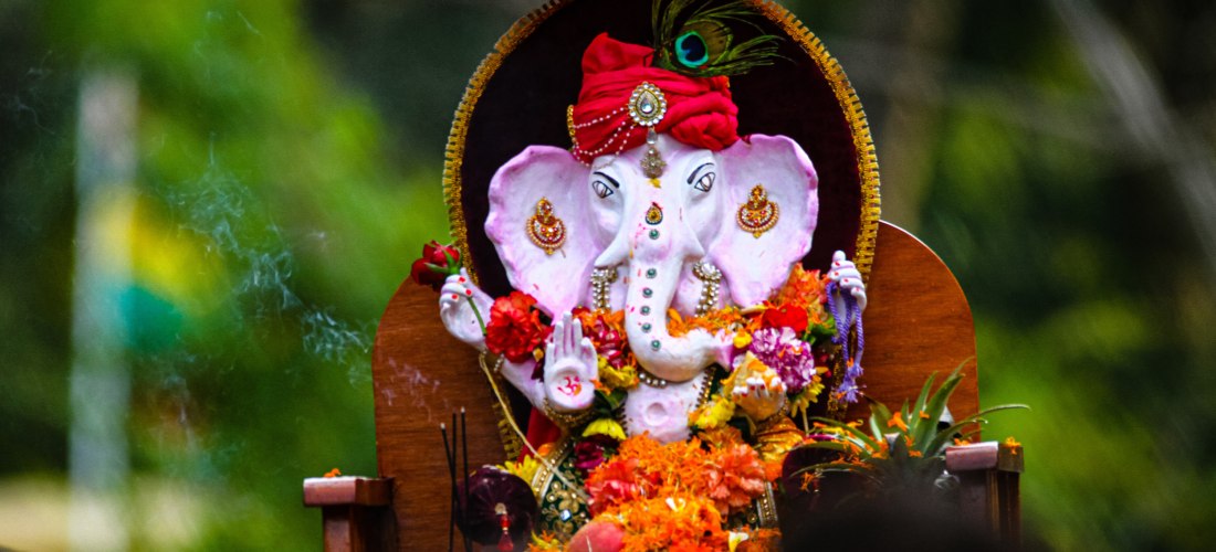 prachtvolle Darstellung des hinduistischen Gottes Ganesha, bekannt als der Beseitiger von Hindernissen und Schutzpatron der Weisheit und des Wohlstands. Die Statue ist kunstvoll geschmückt mit einem roten Turban, Perlenketten und goldenen Verzierungen. Ga