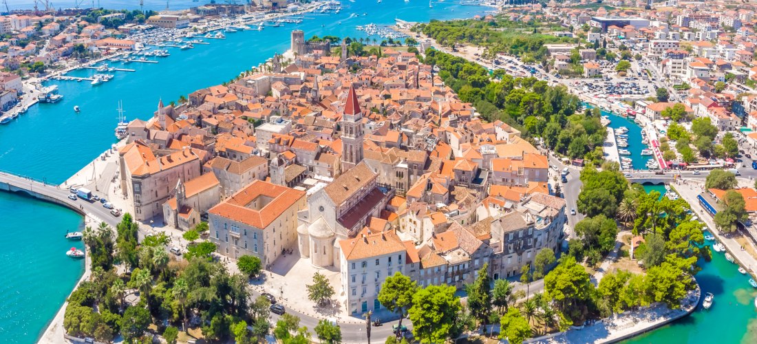 Kroatien - Trogir Luftaufnahme der Altstadt von Trogir in Kroatien. Die mittelalterliche Stadt liegt auf einer kleinen Insel, umgeben von türkisblauem Wasser. Zu sehen sind die historischen Gebäude mit roten Ziegeldächern, der markante Glockenturm der Kathedrale von Trogir