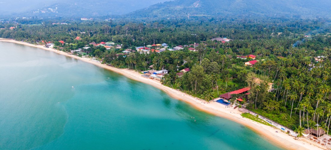 Luftaufnahme vom Lipa Noi Beach auf Koh Samui mit türkisblauem Meer, Palmen und grünen Bergen – idyllischer Strand für Ruhesuchende und Naturliebhaber.