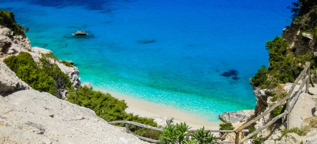 Atemberaubender Blick auf die Cala Goloritzé auf Sardinien mit türkisblauem Meer, weißem Sandstrand und steilen Felsen – einer der schönsten Strände Italiens an der Ostküste Sardiniens.