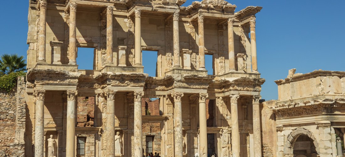 Die Fassade der antiken Celsus-Bibliothek in Ephesos, Türkei. Die gut erhaltene römische Ruine mit ihren hohen Säulen und Statuen zieht zahlreiche Besucher an, die auf den Stufen stehen und das Bauwerk bewundern.