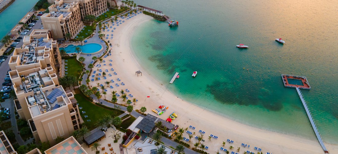 Luftaufnahme eines Luxusresorts mit Strand, Pool, Steg und türkisfarbenem Meer in Ras Al Khaimah – Vereinigte Arabische Emirate.