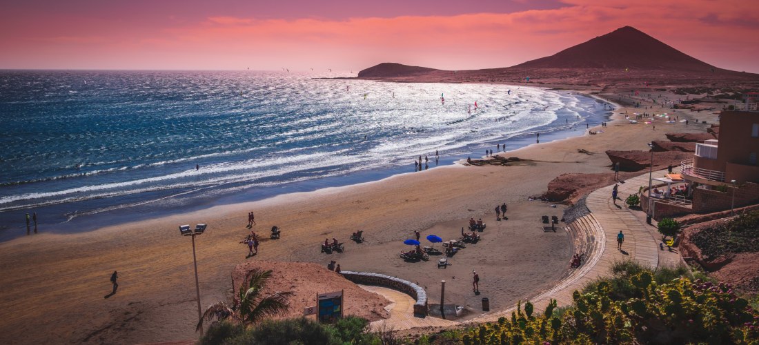 Strand von El Médano bei Sonnenuntergang mit Montaña Roja und Kitesurfern auf Teneriffa