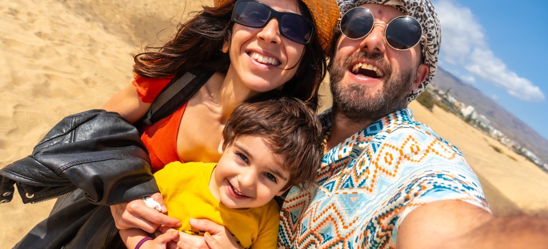 Familienabenteuer in den Dünen von Maspalomas Eine fröhliche Familie macht ein Selfie in den goldgelben Sanddünen von Maspalomas auf Gran Canaria – perfekte Kulisse für gemeinsame Urlaubserinnerungen.