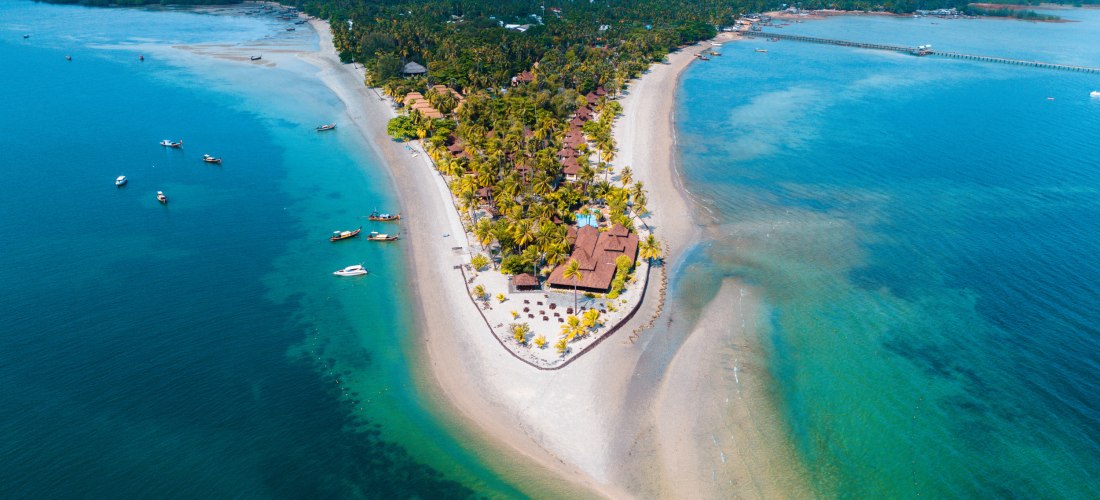 Traumhafte Halbinsel in Südthailand – Luftaufnahme von tropischer Küste mit Resorts und Longtailbooten Luftaufnahme einer tropischen Halbinsel in Thailand mit Stränden, Palmen und traditionellen Longtailbooten im klaren Meer