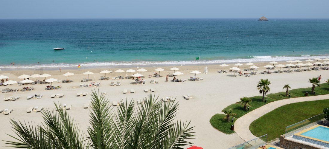 Luxuriöser Strand mit Sonnenschirmen, Liegen und Poolanlage mit Blick auf das blaue Meer