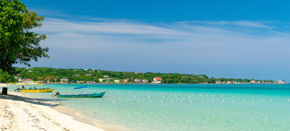 Luxuriöses Strandresort in Negril, Jamaika mit Palmen, weißem Sandstrand und türkisblauem Meer.