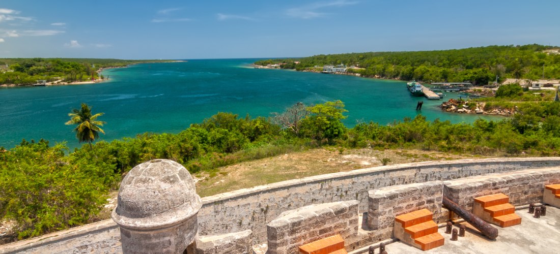 Castillo de Jagua – historische Festung am Eingang der Bucht von Cienfuegos Blick von der historischen Festung Castillo de Jagua auf die Bucht von Cienfuegos auf Kuba mit türkisblauem Wasser, üppiger Vegetation und Hafenanlage im Hintergrund.