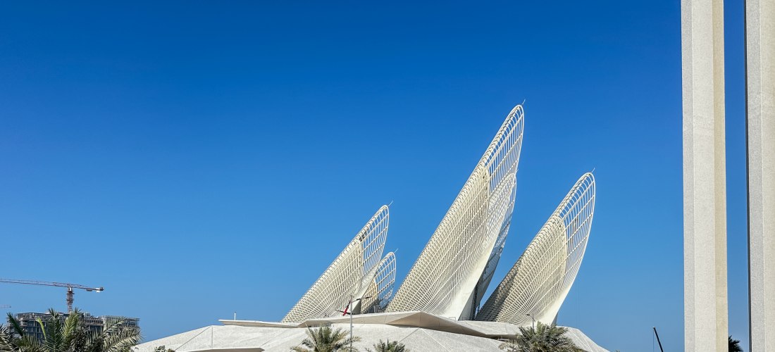 Außenansicht des modernen Abrahamic Family House in Abu Dhabi mit markanter Architektur und Palmen im Vordergrund
