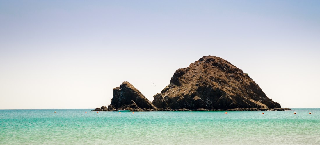 Snoopy Island vor der Küste von Fujairah in den Vereinigten Arabischen Emiraten. Felseninsel im türkisblauen Meer, umgeben von klarem Wasser und Korallenriffen.
