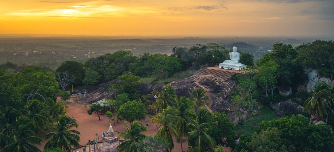 anorama von Mihintale in Sri Lanka mit weißer Buddha-Statue und Tempelanlage im Sonnenuntergang