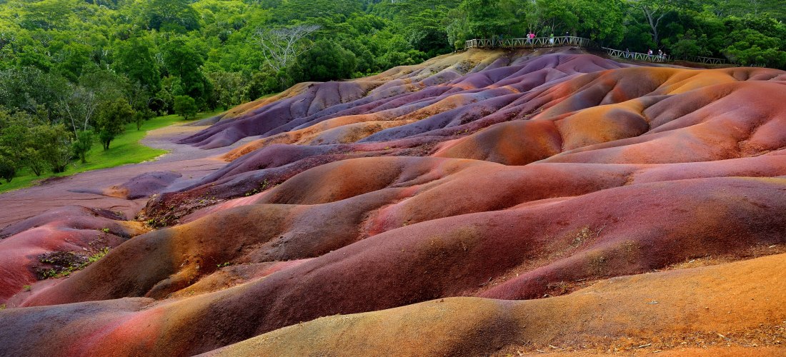 Die Siebenfarbige Erde in Chamarel, Mauritius – wellige Dünenlandschaft in Rot- und Lilatönen, umgeben von tropischem Grün