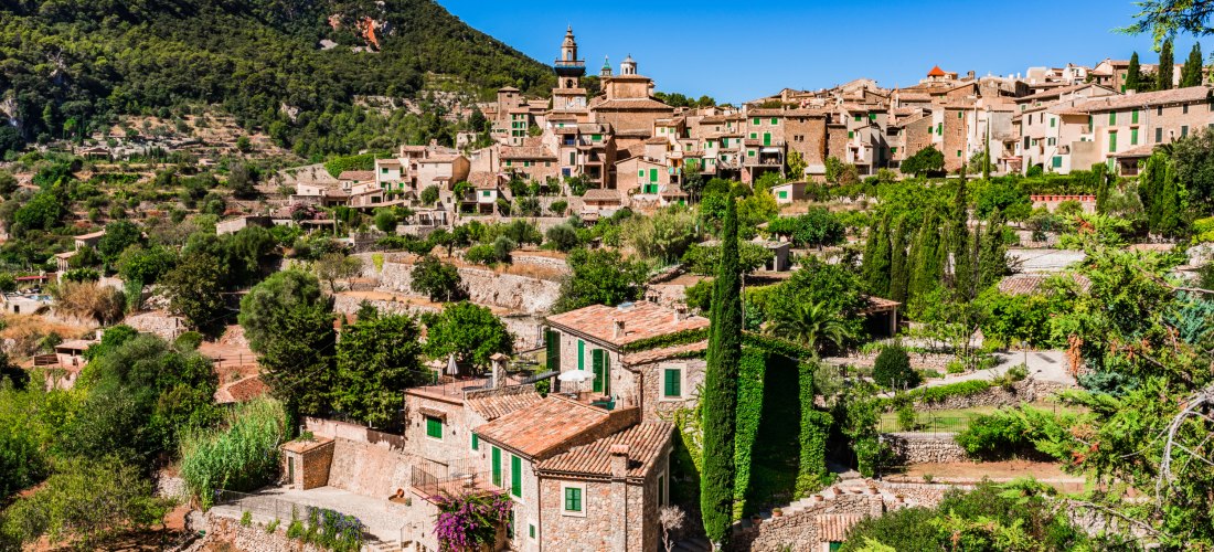 Blick auf das Bergdorf Valldemossa auf Mallorca mit traditionellen Steinhäusern, Gärten und den Bergen der Serra de Tramuntana