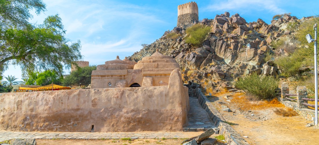 Al-Bidyah-Moschee in Fujairah mit umliegender Felslandschaft und historischem Wachturm. Älteste Moschee der VAE, beliebtes Ausflugsziel und Kulturdenkmal.