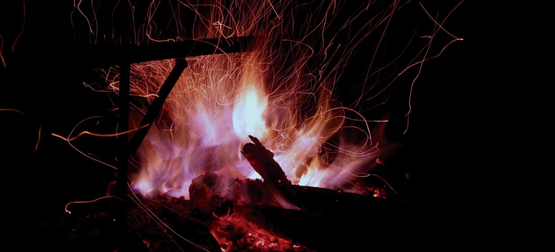 Ein brennendes Lagerfeuer mit intensiven Flammen und Funken, die in die Nacht steigen