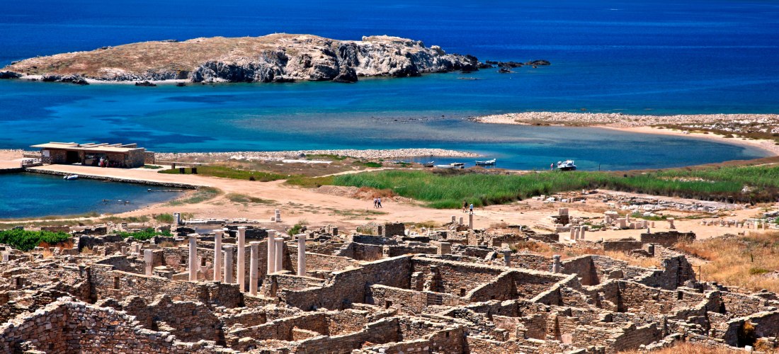 Panoramablick auf die Ruinen der Insel Delos mit antiken Mauern und Säulen vor dem tiefblauen Meer