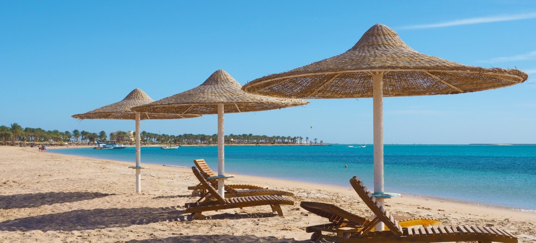 Sonnenliegen und Strohschirme am Strand